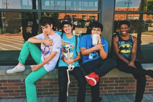 Group of teenage friends sitting outdoors, smiling and having fun together.