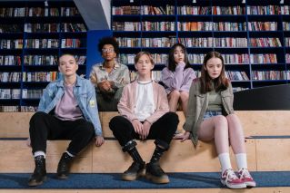 A group of diverse teenagers sitting in a library, showcasing youth diversity and style.